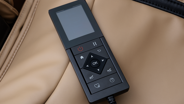 Black massage chair remote with a screen and control buttons on beige leather.
